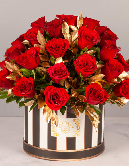 flower bouquet near me - red roses and gold leaves arranged in a striped box